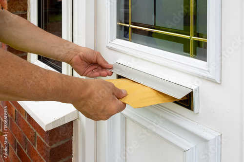 Courier Inserts Bubble Mailer Through Door Slot During Delivery