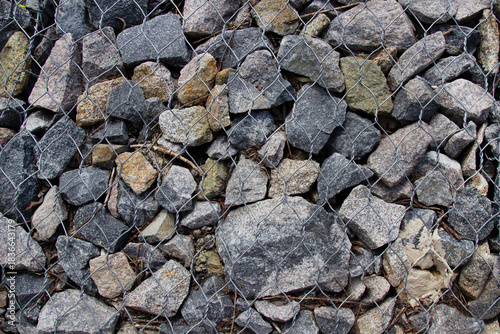Granite stones in a metal mesh. Decorative decoration for the park.