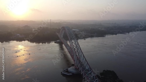 Indonesia, East Kalimantan, Kutai Kartanegara Aerial view of the Red and White Bridge with cars driving under the afternoon sun, July 26, 2024