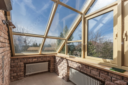 A bright garden room features large windows that invite sunlight, surrounded by a cozy brick interior. The space is perfect for relaxation and enjoying nature's beauty.
