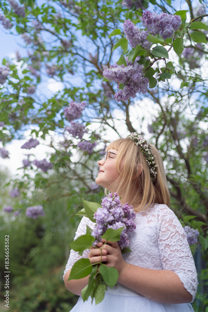 Fototapeta premium Smiling Girl in First Communion Dress with Lilac Blossoms
