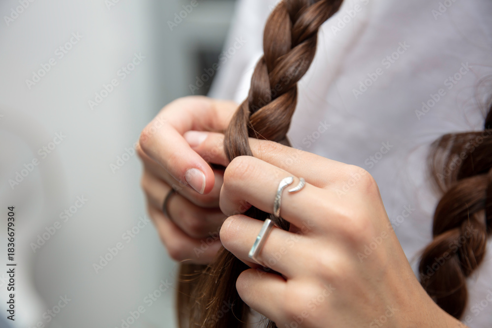 Obraz premium młoda dziewczyna czesze włosy i plecie warkocze