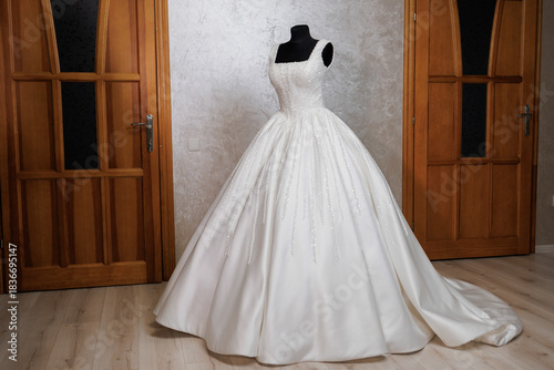Elegant wedding dress displayed in a bright room with wooden doors