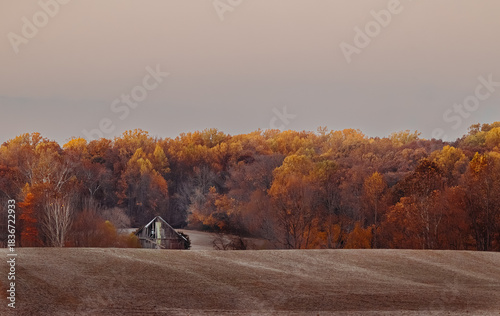 Closeup of a barn on a farm surrounded by autumn foliage 