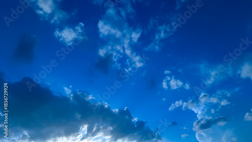 Obraz na plátně A low angle view of a vibrant blue sky filled with fluffy white clouds on a sunn