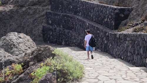 A man with a backpack descends the stairs to a natural pool on the island.