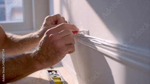 Handyman securing cable management system along a wall at home