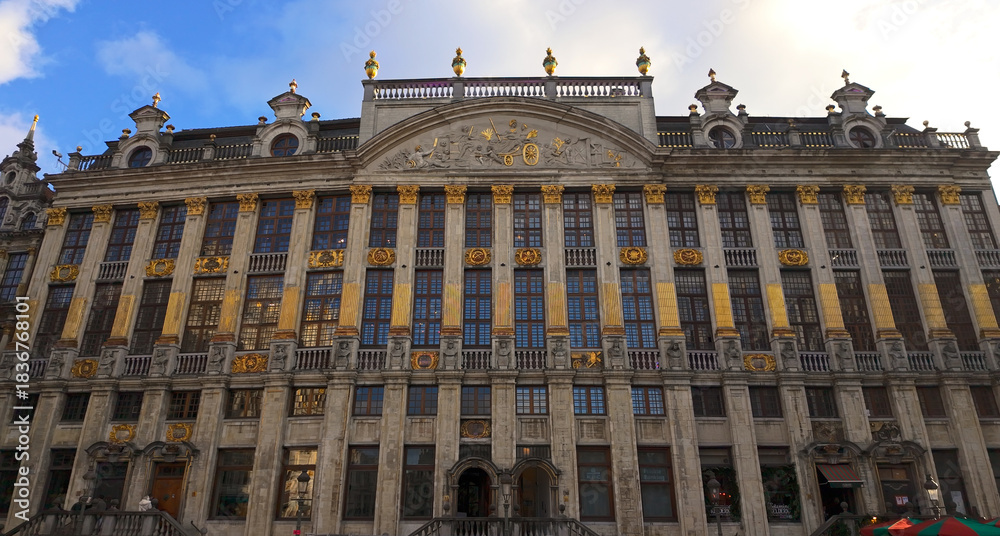 Naklejka premium BRUSSELS, BELGIUM - NOVEMBER 26, 2025 - Historic Grote Markt building showcasing elaborate architecture with golden details under a blue sky