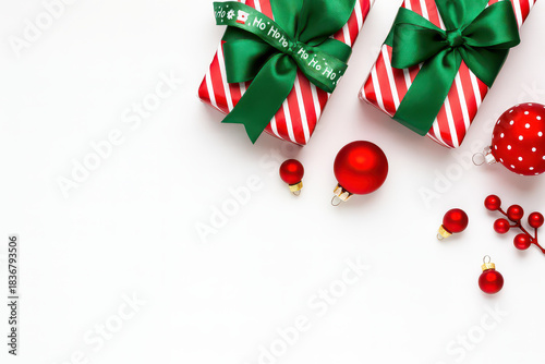 Christmas gift boxes with green ribbon and red baubles on white background for festive joy