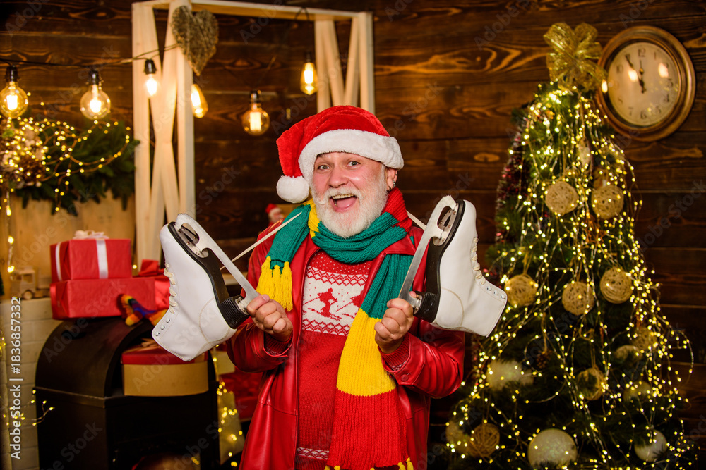 Fototapeta premium Winter leisure. Elderly people fun. Be active. Santa Claus grandfather hold figure skates. Bearded man with pair of skates. Skater christmas gift. Winter fun christmas holidays. Winter sports