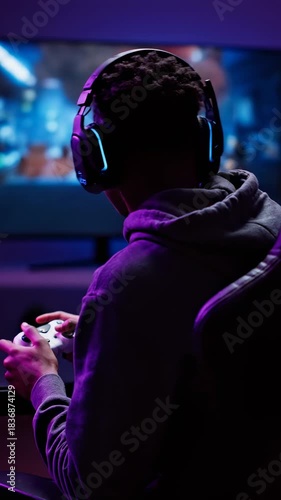 Young Person Wearing Headphones Playing Video Game with Controller in Dark Room Lit by Screen Glow