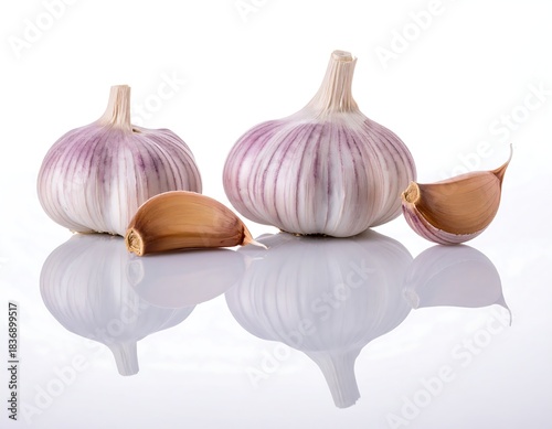 Close-up studio shot featuring two whole bulbs and two cloves, partially separated, against a pristine white background with reflection