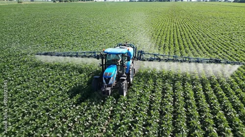 Aerial view of a tractor spraying crops in a vast field, showcasing modern agricultural practices