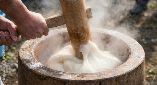 蒸した餅を杵でつく手元のクローズアップ