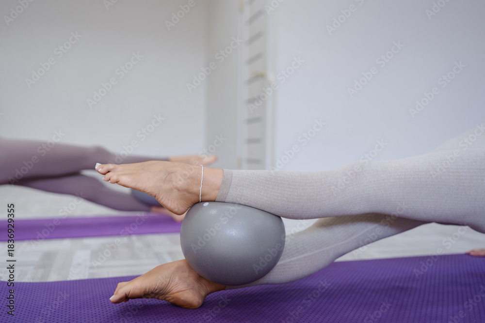 Naklejka premium Pilates ball stability exercise legs using fitness equipment in a bright gym