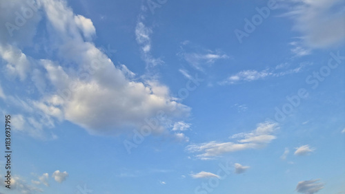 A pale blue sky with light gray and white clouds scattered across it, suggesting an overcast or lightly cloudy day. background style.