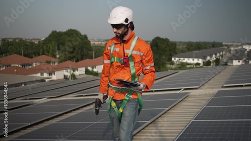 Blue collar worker is inspecting solar panel at rooftop of factory. Energy, sustainability.