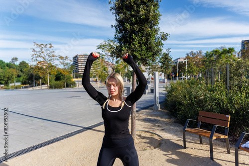 Young woman executing resistance band side-steps on grass wearing fitness gear toning lower body outside
