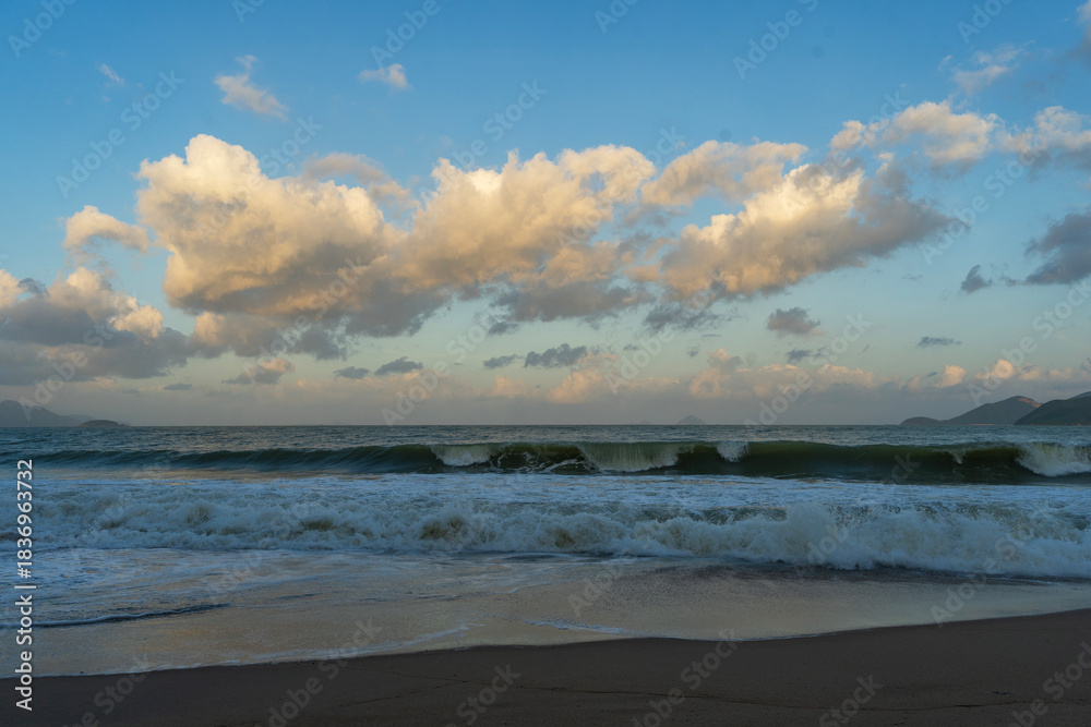 Fototapeta premium Beautiful sunset over the ocean with dramatic clouds and wave.
