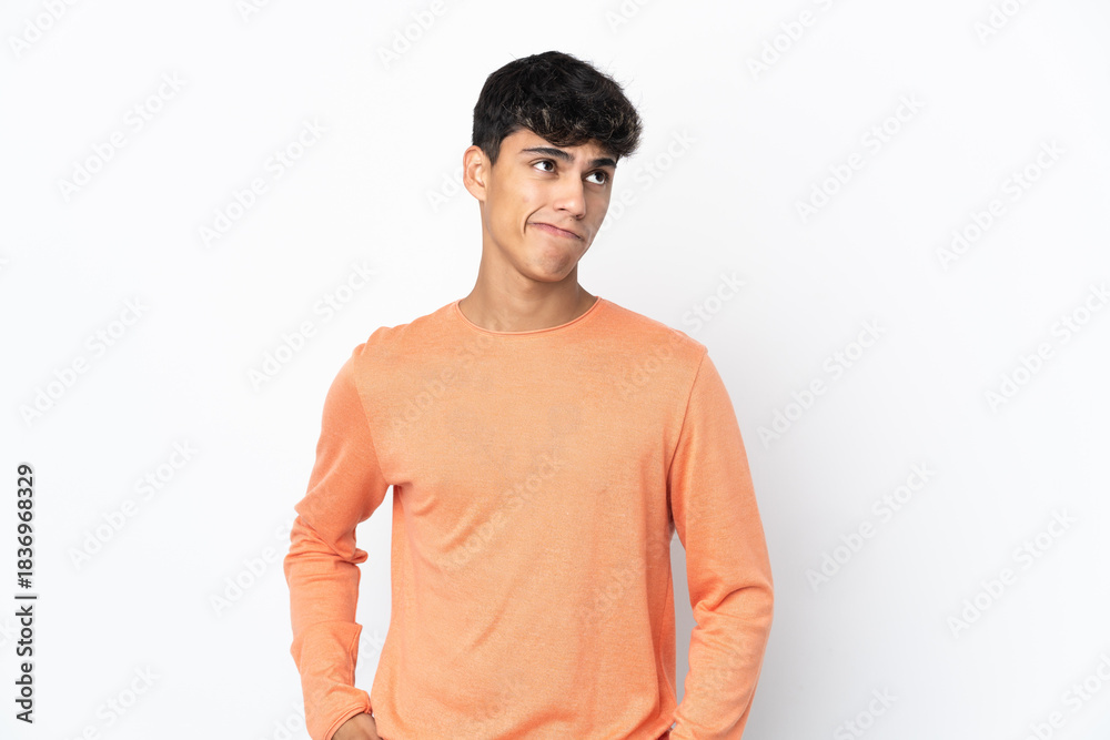 Fototapeta premium Young man over isolated white background having doubts while looking up