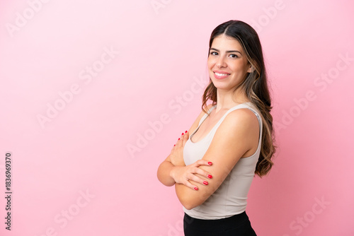 Young Italian woman isolated on pink background with arms crossed and looking forward