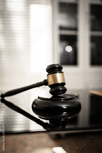 Fotografie A polished wooden gavel resting on a glossy black surface illuminated by soft di