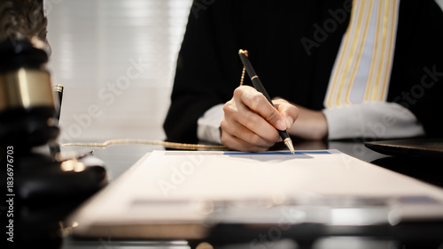 Canvastavla A professional legal expert signs a binding contract at a polished desk, accompanied by a gavel and Lady Justice statue, authority in international trade, cybersecurity, and corporate law sectors