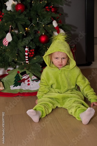 Cute little girl sitting in front of Christmas tree