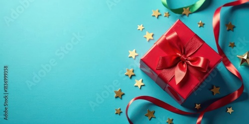A Festive Red Gift Box with a Satin Bow and Golden Stars on a Teal Background