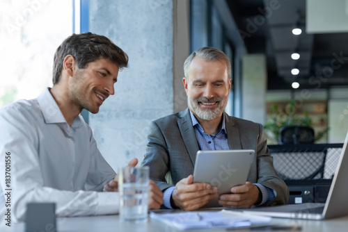 Fotografie Mature businessman using a digital tablet to discuss information with a younger