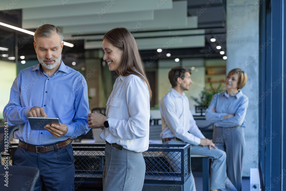 Obraz premium Two business people discussing work together using a tablet in a modern office