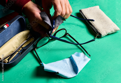 Cleaning glasses. A man's hands with a small microfiber cloth cleaning the lenses of a pair of glasses.