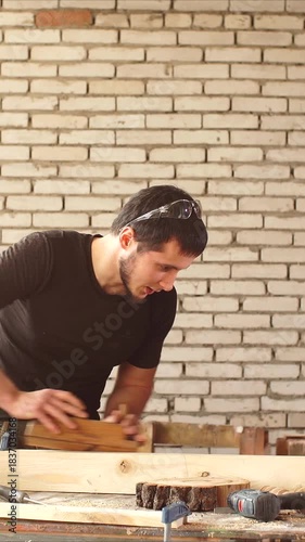 Vertical video of experienced craftsman carefully grinds a wooden board with a plane, preparing wood for furniture manufacture