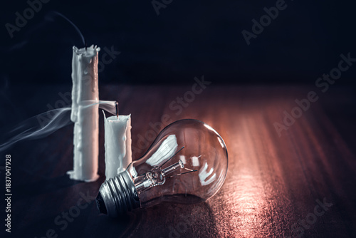 Extinguished candles and a burned-out light bulb on a table—a concept of an energy crisis, power outages, darkness, and resource conservation.