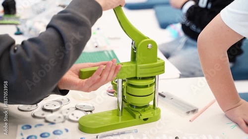 Hands using green button maker, demonstrating crafting process with engaging camera movement