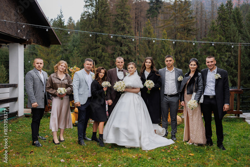 A group of happy wedding guests pose for a photo in a lush green forest