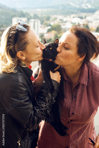 two woman outside kissing black cat, married couple, lifestyle people concept