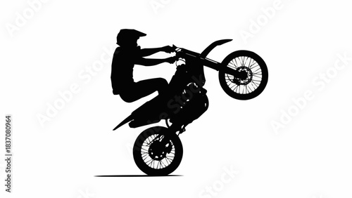 Silhouette of a motocross rider performing a wheelie on a dirt bike.