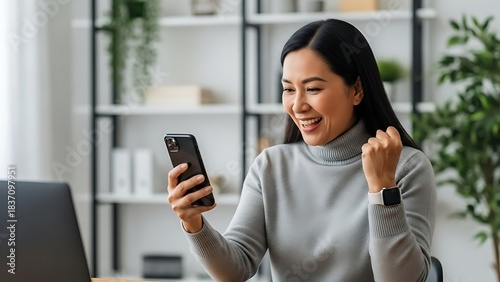 Excited Asian Woman Celebrating Success on Smartphone.