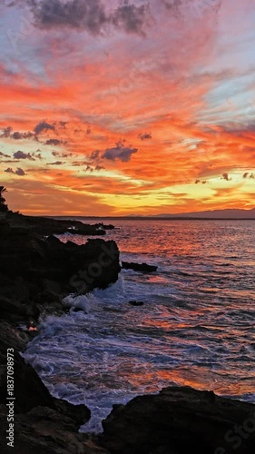 Golden sunset light illuminates  rocky shore of Mallorca, Spain. Vertical. Tranquil Mediterranean scene perfect for travel footage, peaceful backgrounds, or nature themed visuals.