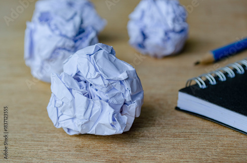 Fotografija A closeup view of crumpled sheets of paper resting near a spiral notebook and pencil