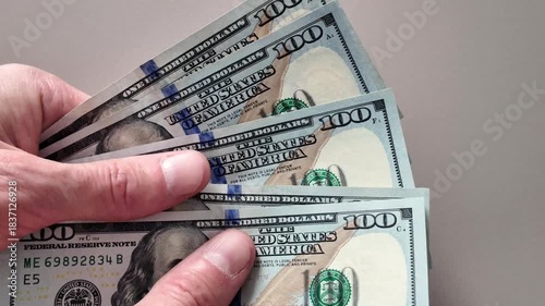 Close-up of a man's hands counting a stack of US hundred dollar bills