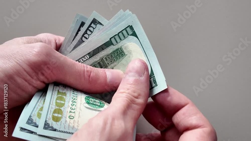 Close-up of male hands counting a stack of us one-hundred-dollar bills. Concept of payment, wealth, cash flow, and financial success