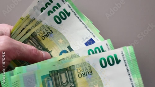 Close-up of a person's hands counting a wad of one hundred euro banknotes. Concept of wealth, salary, income, and financial success