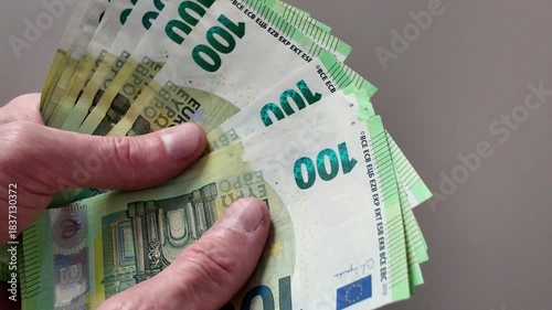 A man's hands count a wad of one hundred euro banknotes