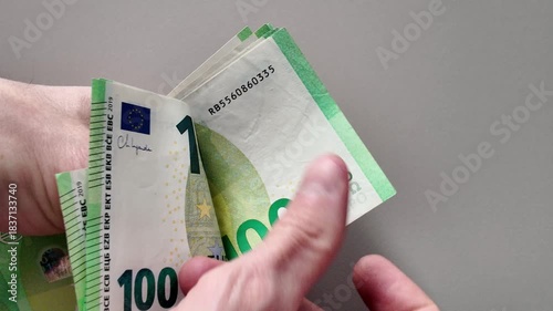 Close-up of a man's hands counting a stack of one hundred euro banknotes