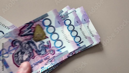 A man's hands count a stack of 10,000 Kazakhstani tenge banknotes