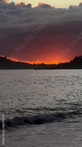 Spectacular red sunset with clouds over ocean waves and coastline
