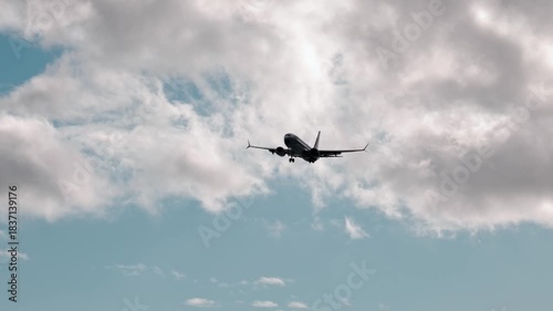 Airplane landing at sunset, camera pans and zooms in on descent through clouds