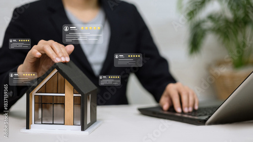 Business person touching house model with virtual five star rating and review icons.